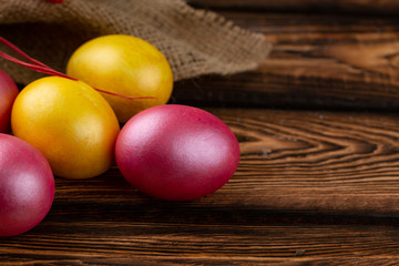 Easter eggs on a sackcloth and wooden background. Happy easter Bright multicolored shiny easter eggs. Background with easter eggs.