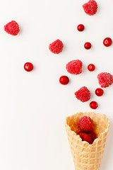 Ice cream cone filled with .raspberry and cranberries on a white background. Frosen berries .fall out from a waffle cone. Summer concept.