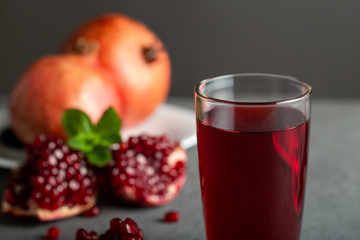Pomegranate juice in a glass on gray background.