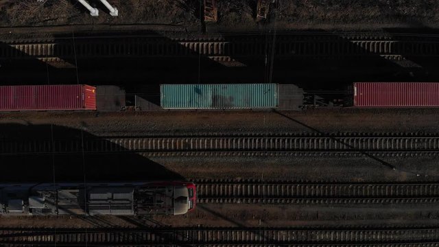 Aerial view of a large train on the rails next to the river. The camera flies over a long train of tanks standing on the rails