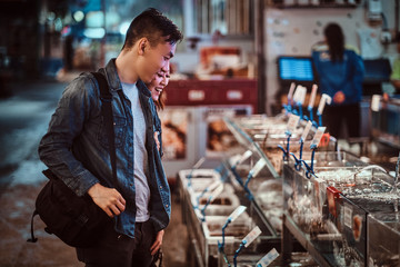Smiling asian couple are choosing seafood at market.