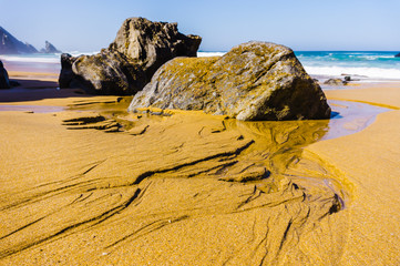 Flows of water on sandy Rocky Adraga beach