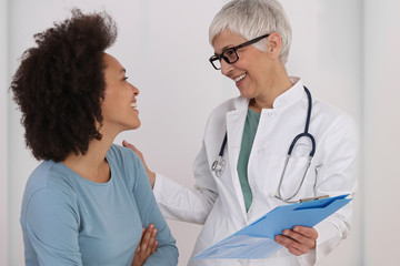 Mature Doctor comforting young Woman Patient. Good news concept. Professional medical help,support, advice Female health , gynecology concept