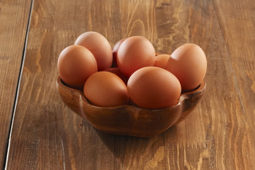 Wooden plate with raw eggs on a table, close-up view