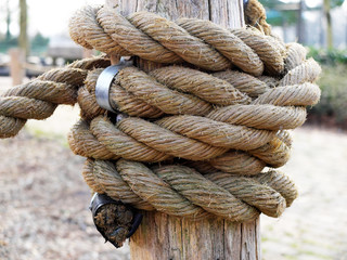 Fototapeta na wymiar Thick rope on a wooden column forming a knot as part of the rope fence.