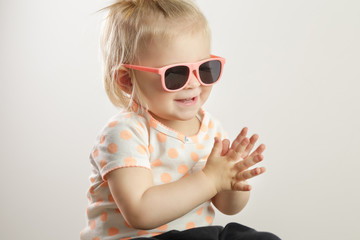 Studio shot of an adorable baby girl wearing sunglasses and clapping hands, the importance of exposing children to music concept