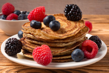 Pancakes with blueberries and strawberries and cup of red juice on wooden background. Close Up. Soft focus.