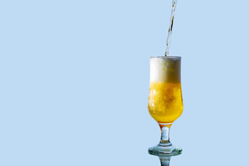 Fresh beer pours into a glass and spills around making a lot of foam, isolated photographed