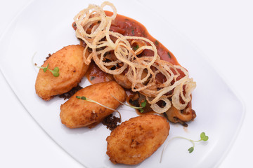 potato zrazy - traditional Ukrainian dish -  decorated with mushrooms and onion on white restaurant plate