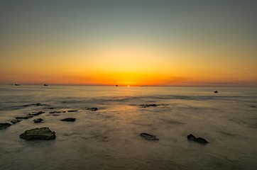 Paesaggio marino con scogli che affiorano dal mare al tramonto