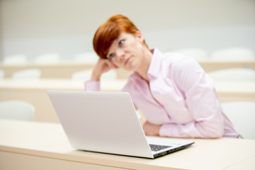 Fototapeta premium young woman works with a laptop in classrooms at the university. She studies and prepares homework as a student and teacher