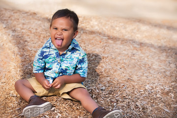 A playful or mischievous 2 year old boy sticking his tongue out making a facial gesture.