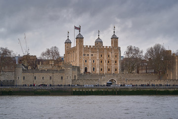 Cityscape Picture of Tower of London and Thames river during cloudy and windy day, british gothic castle, fortress and prison in London city from tudor age with treasury of royal crown and jewels.