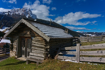 Fototapeta na wymiar Wooden chalet with snow and ice with a view onto Langkofel Dolomites mountain peak on the Seiser Alm, South Tyrol, Italy in winter.