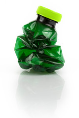 Crushed dark green plastic bottle on white background. Still-life picture taken in studio with soft-box