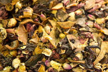Herbal oriental tea with flower blossom like pink rose, fruit pieces and tea leaves. Close up. 