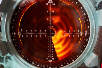 Old fashioned analog military orange light radar screen for using maily in warships, cruisers, submarines or battle ships for detections of enemies activites like ships or attacking fighter planes.