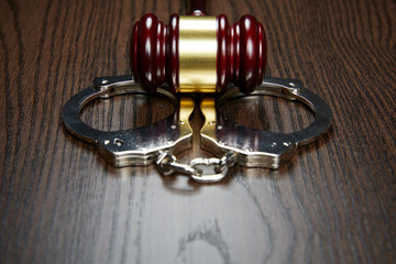 GAVEL AND HANDCUFFS ON WOOD