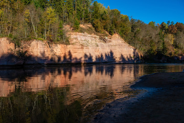 beautiful golden sunrise over forest river with sandstone cliffs on the shores