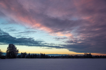 colorful sunset light over fields of snow in winter