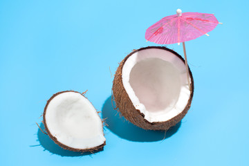 Fresh juicy coconut with a cocktail umbrella isolated on a blue background. Concept of Healthy eating and dieting. Travel and holiday concept