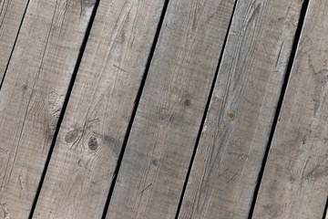 Outdoor wooden flooring from the planks. Knots, scratches and black lines between the boards. Texture for background.