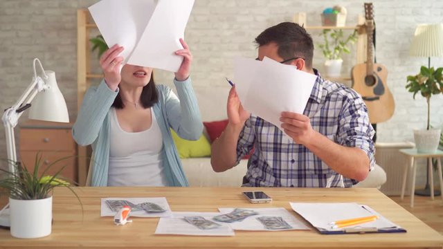 Young couple quarrels while making calculations of documents at home with a calculator