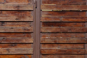 brown wooden background of thin boards in the wall of the fence on the street
