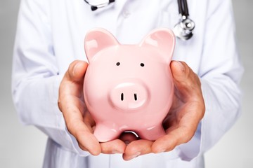 Doctor with Stethoscope Holding Piggy Bank close up