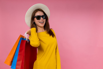 cheerful young asia woman holding shopping bags over pink background © sittipun