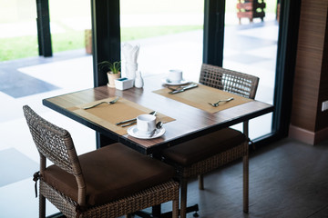 Empty restaurant part of hotel with table and armchair near windows.