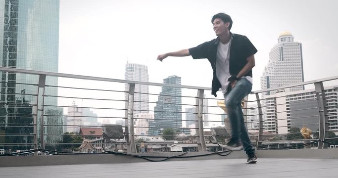 Young Man Doing Street Dancing In Front Of Pier In Background. Asian Man.