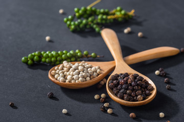 Close-up of ground black pepper in wooden spoon on black table