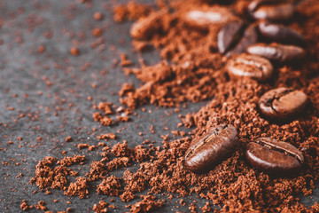 close-up of coffee powder and beans splash on black wooden board