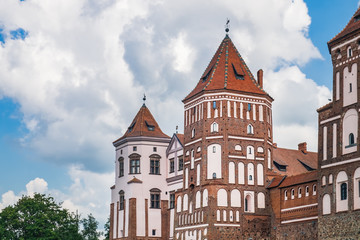 Fototapeta na wymiar Medieval castle in Mir, Belarus. Side view of towers under cloudy sky in summertime