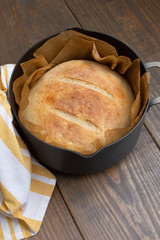 Round Loaf of Freshly Baked Sourdough Bread in Parchment Lined Dutch Oven