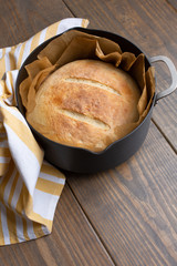 Round Loaf of Freshly Baked Sourdough Bread in Parchment Lined Dutch Oven