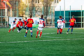 Obraz premium Young footballers dribble and kick football ball in game. Boys in yellow white sportswear running on soccer field.Training, active lifestyle, sport, children activity concept 