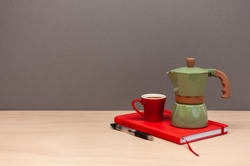 italian coffee maker small cup and red notebook