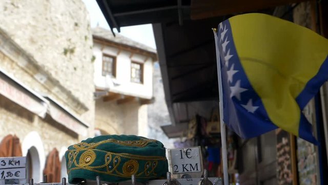 Small flag of Bosnia and Herzegovina fluttering in the wind beside a traditional skullcap or taqiyah