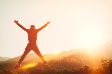 Fototapeta na wymiar Happy man jumping at top of mountain with sunset sky abstract background.