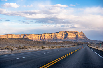 Straight divided long road abutting against the horizon in Arizona with mountain hills and desert plateau