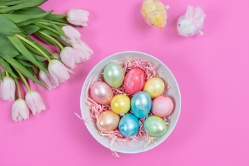 Fototapeta na wymiar Colored Easter eggs, tulips and toys on pink background