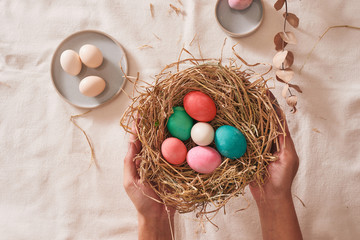 Beautiful Easter multi color egg in straw on wooden background, Easter day concept
