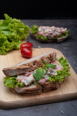 Healthy breakfast sandwiches with tomato, lettuce on gray board as background