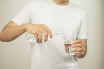 man hand holding a bottle of water Pouring water into a glass.