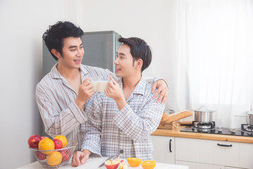 Young asian male homosexual couple drinking milk for breakfast in kitchen