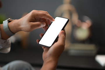Cropped shot of man holding his blank mobile smartphone during work in office
