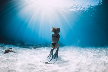 Freediver young woman with fins swim underwater in ocean
