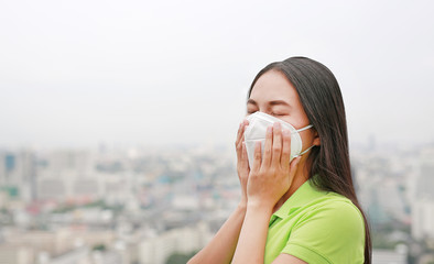 Asian woman breathing by wearing a protection mask against PM 2.5 air pollution in Bangkok city....